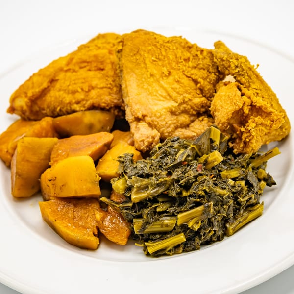 A plate of crispy fried chicken, sweet potato chunks, and collard greens from Selby's Grab and Go.